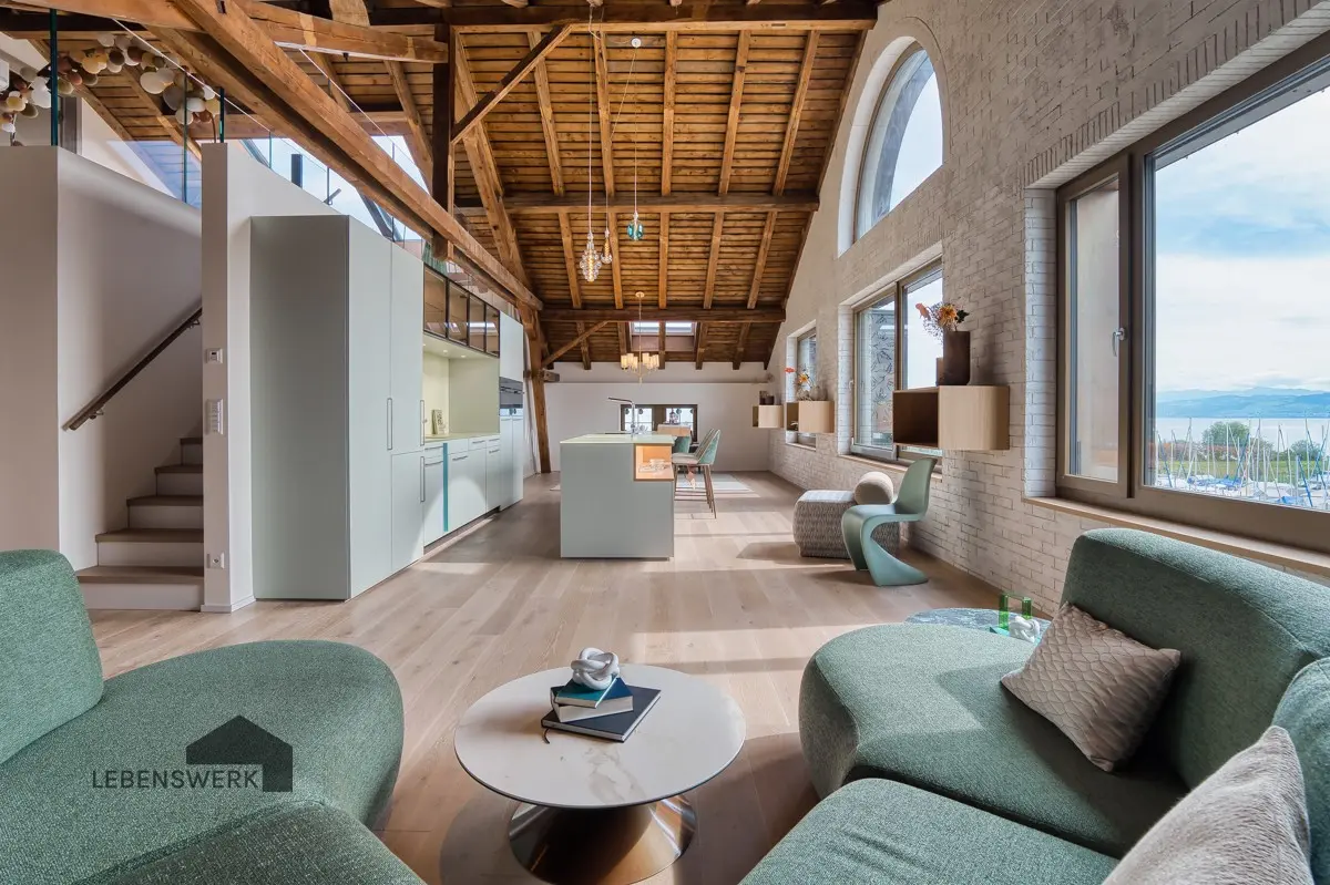 Die gemütliche Lounge lädt zum Ankommen, Lesen oder einem Glas Wein ein, während die Sonne durch die grossen Fenster den Raum in warmes Licht taucht