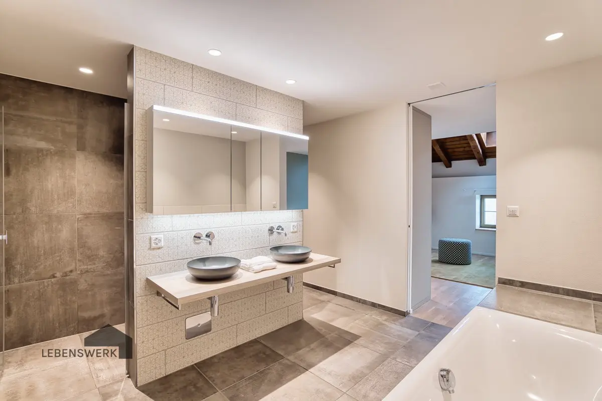 Das grosszügige Masterbad en Suite überzeugt mit Badewanne, begehbarer Dusche mit Glaswand, einem eleganten Doppellavabo und hochwertigen Armaturen