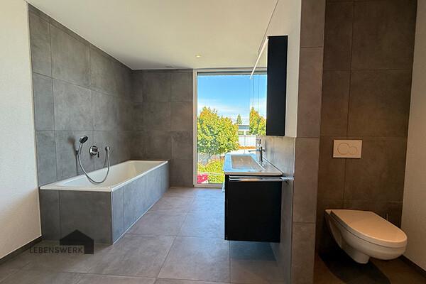 Helles Bad mit edlen Feinsteinzeugplatten und bodentiefem Fenster