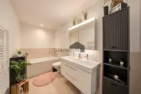 Einladendes Badezimmer mit Badewanne und grosszügigem Waschtisch für entspannte Alltagsmomente.