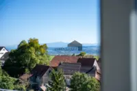 Die erhöhte Lage bietet einen weiten Blick über die grüne Landschaft bis zu den Alpen.
