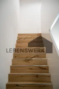 Die Treppe in warmer Holzoptik verbindet die drei Wohnebenen und setzt einen wohnlichen Akzent.
