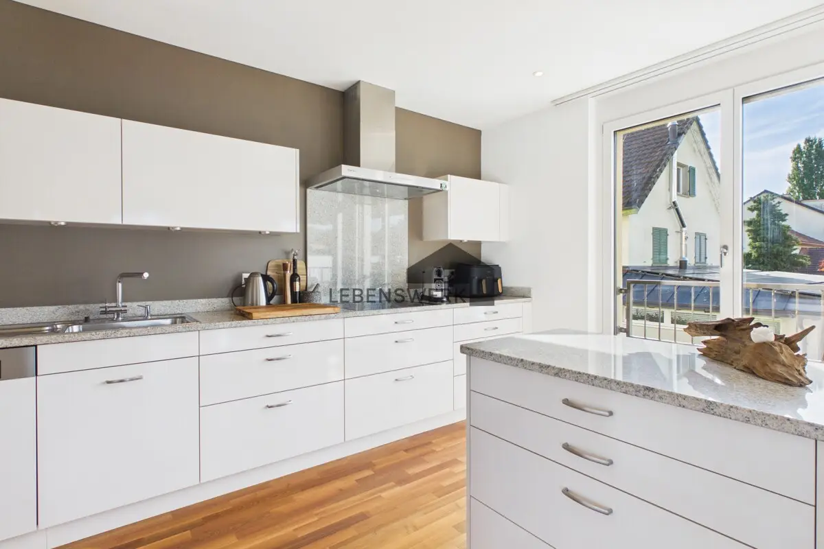 Helle, moderne Küche mit grosszügiger Arbeitsfläche und direktem Zugang zum Balkon.