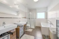 Grosses Badezimmer mit Badewanne und Eckdusche