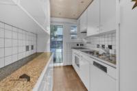 Freundliche Küche mit Einbauschränken und Zugang zum Balkon