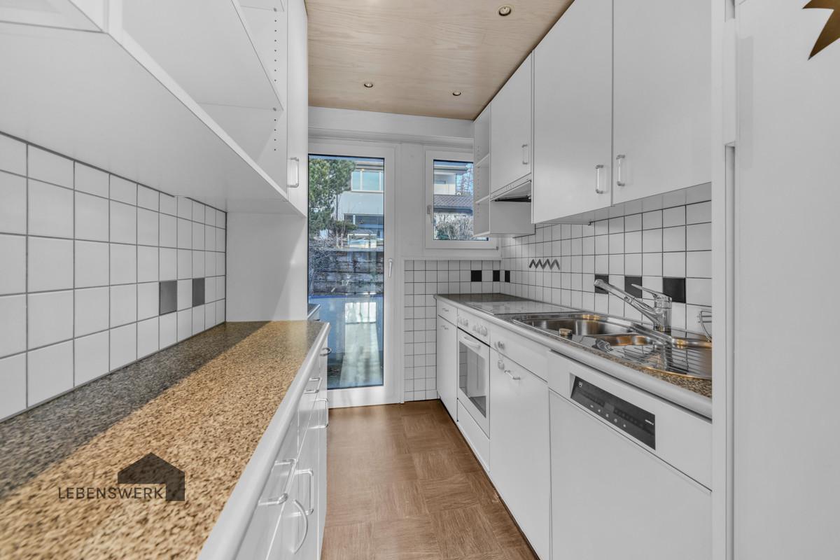 Freundliche Küche mit Einbauschränken und Zugang zum Balkon