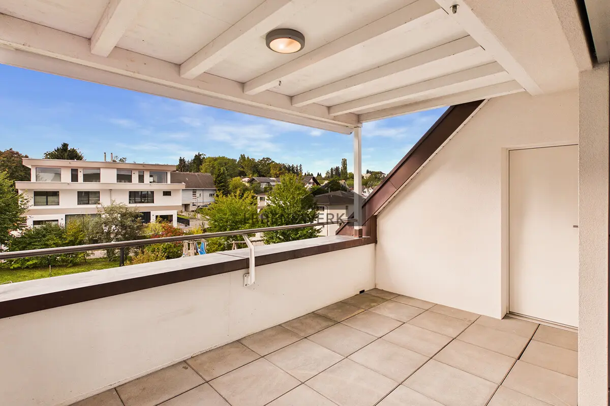Gedeckte Loggia mit Blick ins grüne Wohnquartier