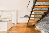 Architektonisches Highlight. Freitragende Holztreppe mit Glasgeländer und Natursteinwand