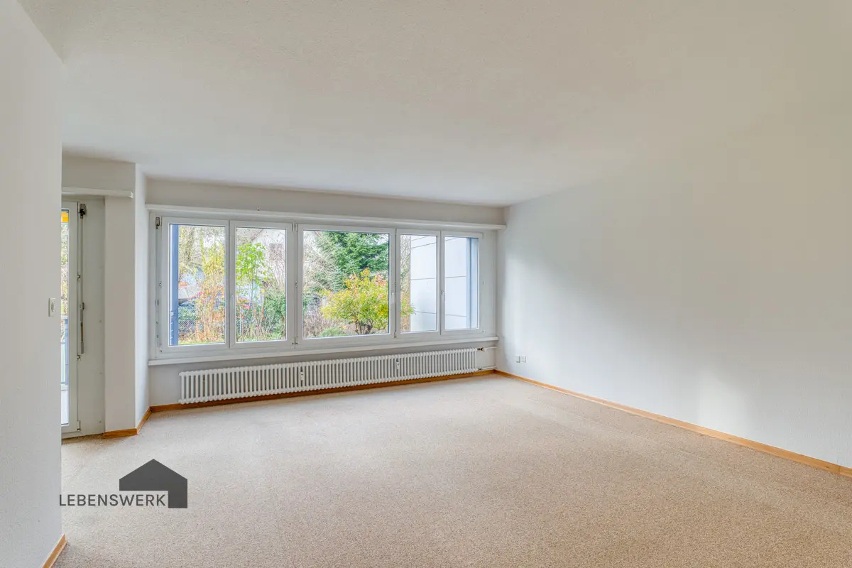 Wohnzimmer mit grosser Fensterfront und Blick ins Grüne